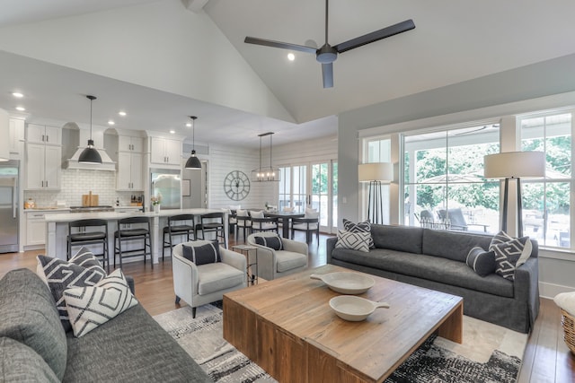 living room featuring high vaulted ceiling, ceiling fan, a wealth of natural light, and light hardwood / wood-style flooring