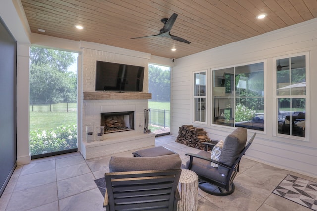 living room with wooden ceiling, ceiling fan, a brick fireplace, and light tile floors