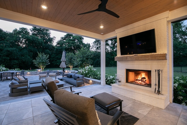 view of terrace featuring ceiling fan and an outdoor living space with a fireplace