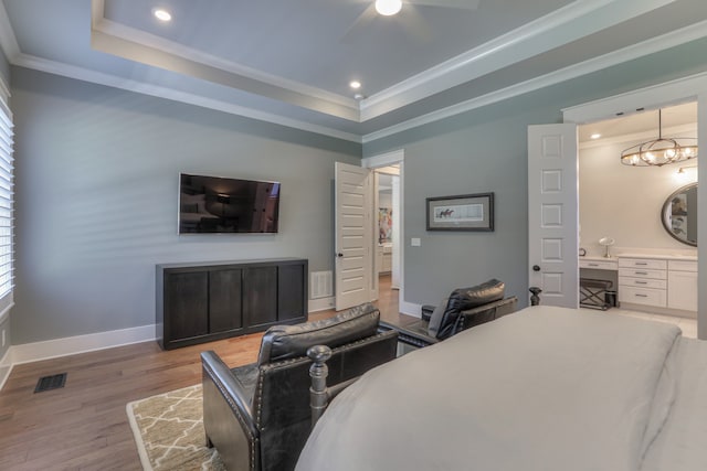 bedroom featuring crown molding, a raised ceiling, light wood-type flooring, and ceiling fan with notable chandelier