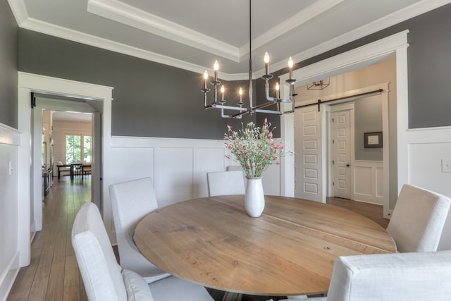 dining area with a chandelier, a tray ceiling, a barn door, and hardwood / wood-style flooring