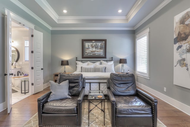 bedroom featuring a raised ceiling, ensuite bathroom, ornamental molding, and hardwood / wood-style flooring