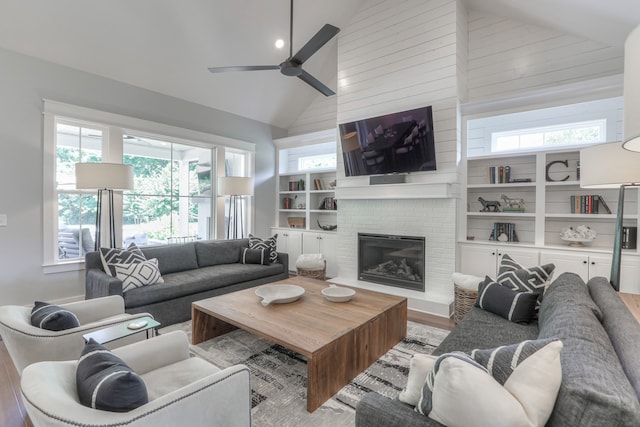 living room with ceiling fan, high vaulted ceiling, light wood-type flooring, and a fireplace