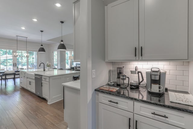 kitchen with pendant lighting, tasteful backsplash, dark stone countertops, white cabinetry, and dark hardwood / wood-style floors