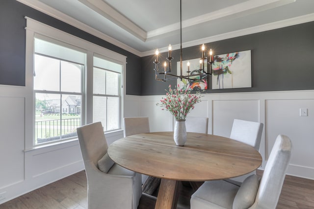 dining room with ornamental molding, dark hardwood / wood-style floors, a chandelier, and a tray ceiling