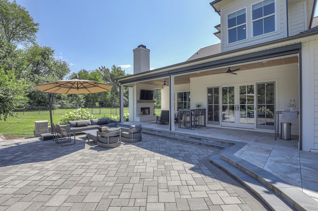 view of patio with ceiling fan, an outdoor living space with a fire pit, and french doors