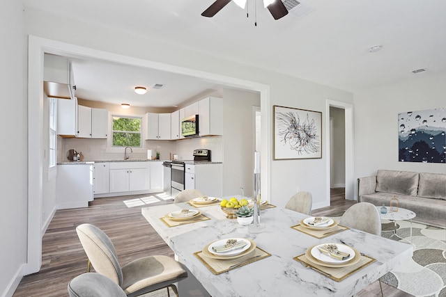 dining space featuring hardwood / wood-style floors, ceiling fan, and sink