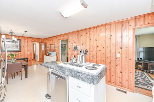 kitchen featuring stainless steel dishwasher, wood walls, white cabinetry, and light tile floors