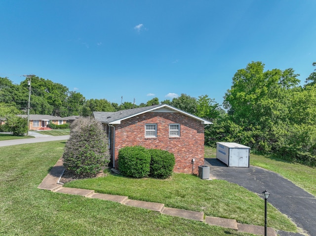 view of front of home featuring a front lawn and a storage shed