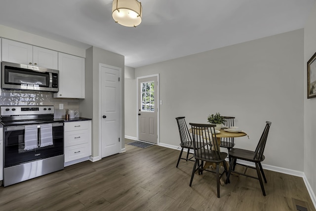 kitchen with backsplash, dark hardwood / wood-style floors, stainless steel appliances, and white cabinets