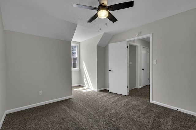 bonus room with a textured ceiling, ceiling fan, and dark colored carpet