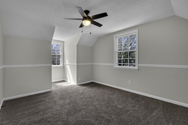 bonus room featuring ceiling fan, dark colored carpet, vaulted ceiling, and a textured ceiling