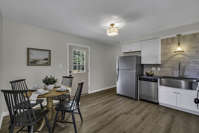 kitchen featuring hanging light fixtures, white cabinetry, dark wood-type flooring, appliances with stainless steel finishes, and sink