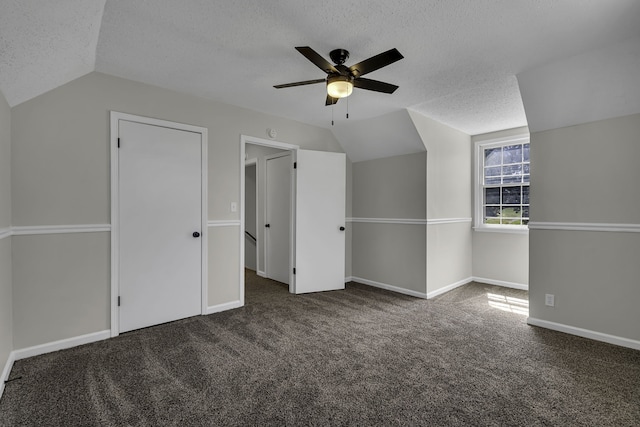 additional living space featuring ceiling fan, lofted ceiling, dark colored carpet, and a textured ceiling