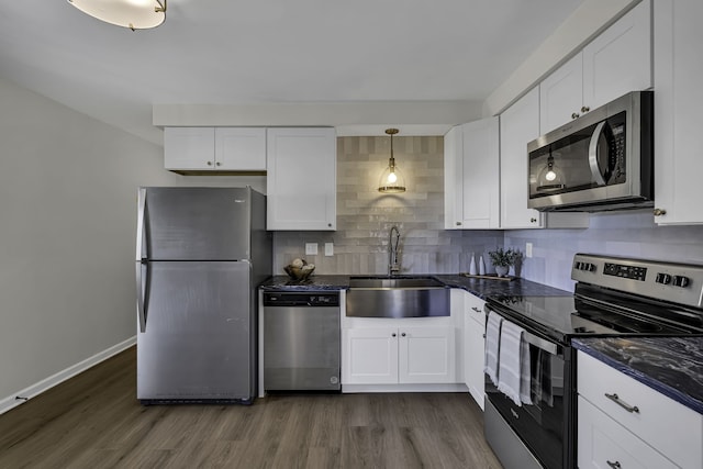 kitchen featuring appliances with stainless steel finishes, pendant lighting, dark hardwood / wood-style flooring, sink, and white cabinets