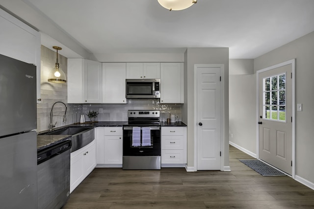 kitchen featuring tasteful backsplash, white cabinetry, stainless steel appliances, and decorative light fixtures