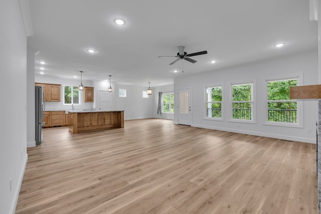 unfurnished living room featuring plenty of natural light, light hardwood / wood-style floors, and ceiling fan