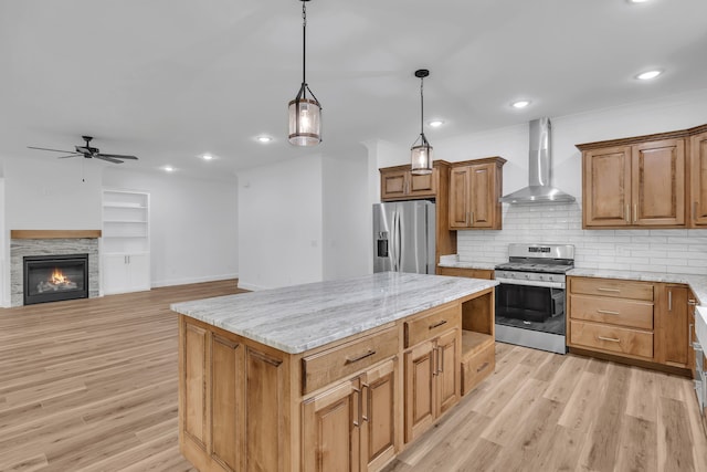 kitchen with wall chimney exhaust hood, light hardwood / wood-style floors, appliances with stainless steel finishes, and a center island