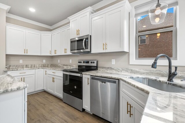 kitchen with white cabinets, pendant lighting, light hardwood / wood-style floors, and stainless steel appliances