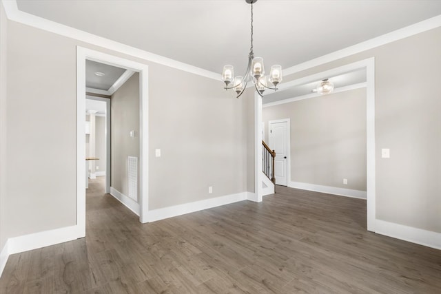 empty room featuring crown molding, dark hardwood / wood-style floors, and an inviting chandelier