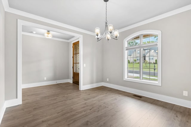 spare room with dark hardwood / wood-style flooring, ornamental molding, plenty of natural light, and a chandelier