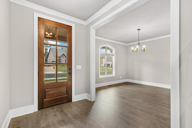 foyer with a notable chandelier, ornamental molding, and dark hardwood / wood-style floors