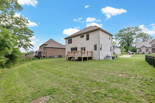 rear view of property with a wooden deck, central air condition unit, and a yard