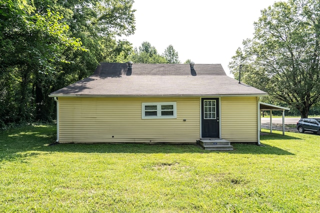 back of property with a carport and a lawn