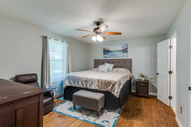 bedroom featuring a textured ceiling, wood-type flooring, and ceiling fan