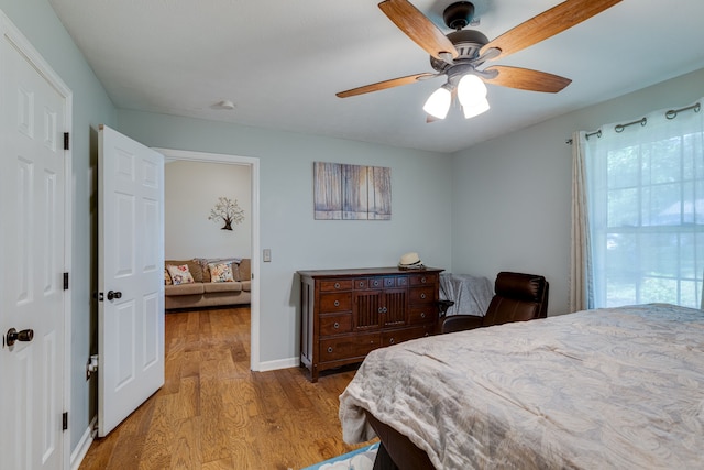 bedroom featuring ceiling fan, light hardwood / wood-style flooring, and multiple windows