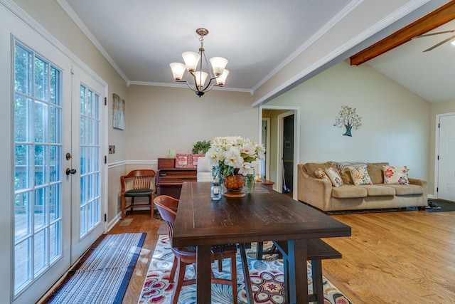 dining room with french doors, hardwood / wood-style floors, ornamental molding, ceiling fan with notable chandelier, and vaulted ceiling with beams