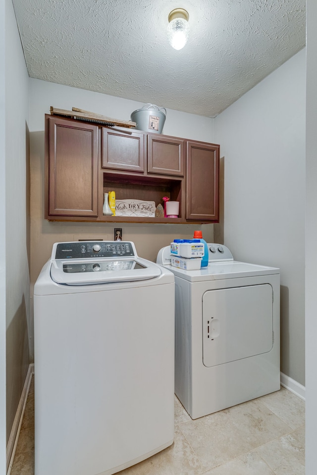 clothes washing area featuring a textured ceiling, cabinets, separate washer and dryer, and light tile floors