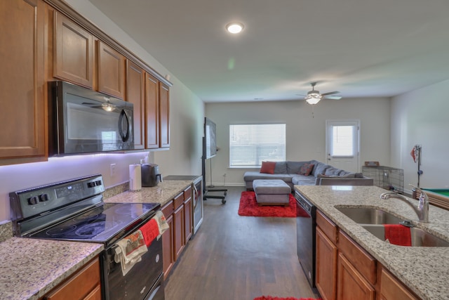 kitchen with light stone countertops, ceiling fan, dark wood-type flooring, black appliances, and sink