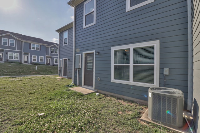 back of house with central air condition unit and a lawn