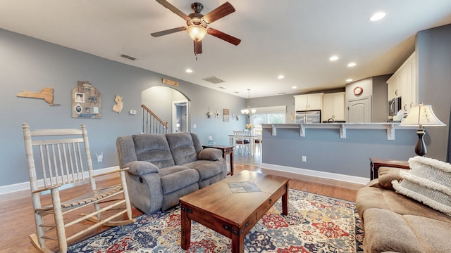 living room featuring light hardwood / wood-style floors and ceiling fan with notable chandelier