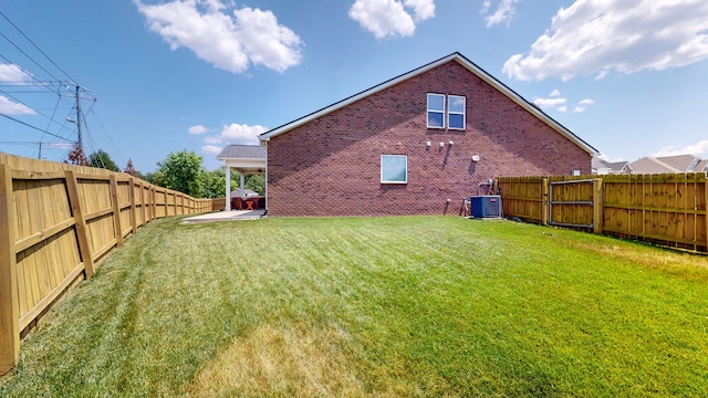 rear view of property featuring central AC unit, a lawn, and a patio area