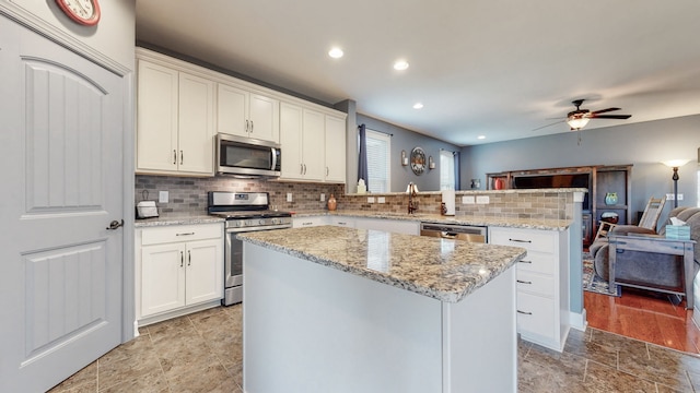 kitchen featuring tasteful backsplash, a center island, ceiling fan, stainless steel appliances, and light hardwood / wood-style flooring