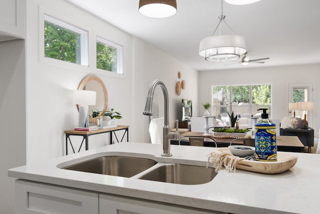 kitchen with white cabinets, plenty of natural light, decorative light fixtures, and light stone countertops