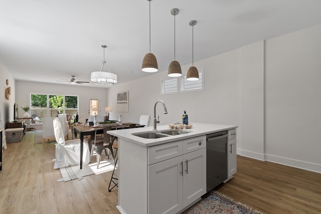 kitchen featuring a kitchen island with sink, ceiling fan, sink, and pendant lighting