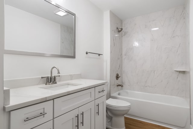 full bathroom with tiled shower / bath combo, toilet, vanity, and wood-type flooring