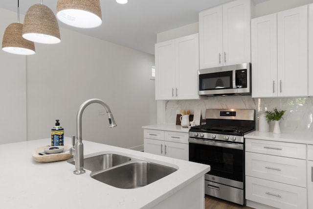 kitchen featuring appliances with stainless steel finishes, tasteful backsplash, white cabinetry, sink, and hanging light fixtures