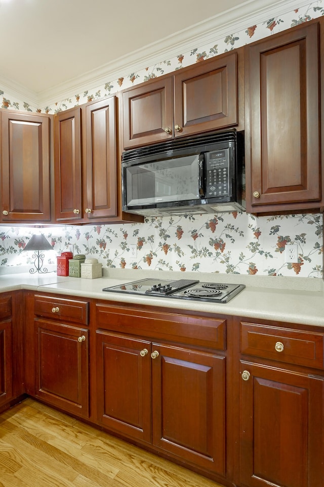 kitchen featuring light wood-type flooring, ornamental molding, and gas stovetop