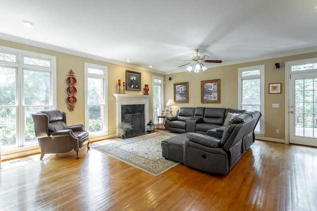 living room with light hardwood / wood-style flooring, ceiling fan, crown molding, and a healthy amount of sunlight