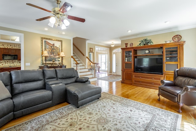 living room with ceiling fan, ornamental molding, and light hardwood / wood-style flooring