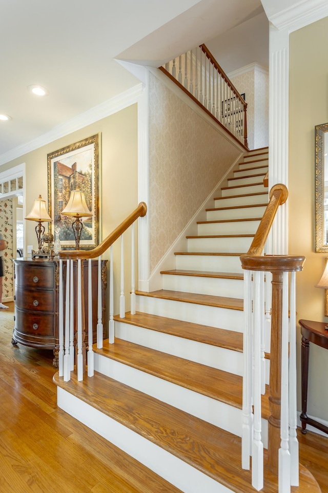 stairway with crown molding and light hardwood / wood-style floors