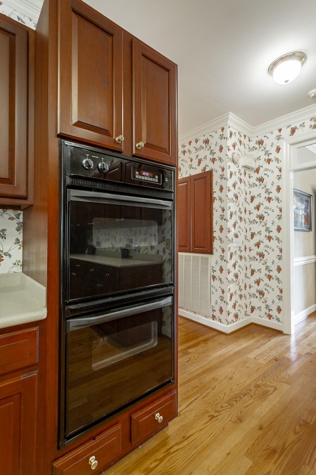 kitchen featuring double oven, crown molding, and light wood-type flooring