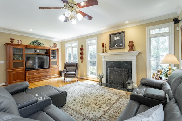 living room featuring ceiling fan, light wood-type flooring, ornamental molding, and a premium fireplace