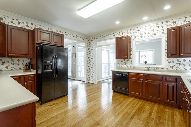 kitchen featuring crown molding, light hardwood / wood-style flooring, black appliances, and sink