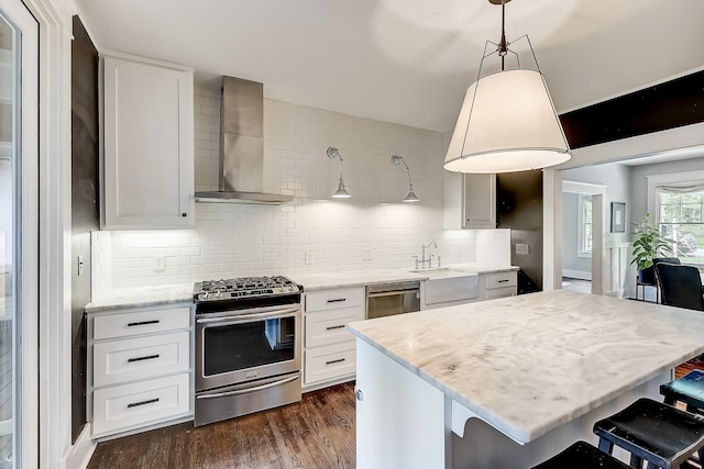 kitchen featuring tasteful backsplash, wall chimney range hood, a breakfast bar area, stainless steel appliances, and dark hardwood / wood-style flooring