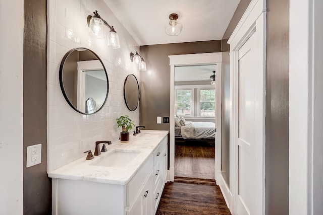 bathroom featuring dual sinks, tasteful backsplash, hardwood / wood-style flooring, ceiling fan, and large vanity